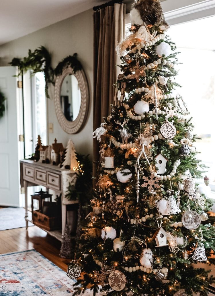 a decorated Christmas tree and a white entryway table and mirror