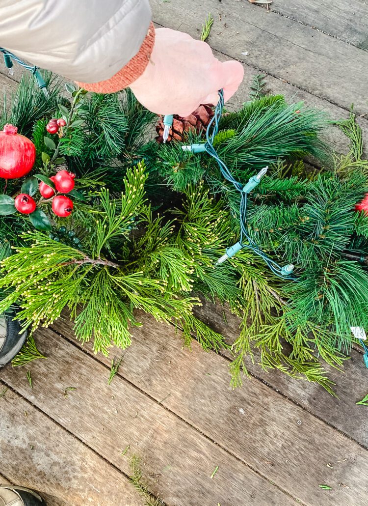 adding Christmas lights to a garland.