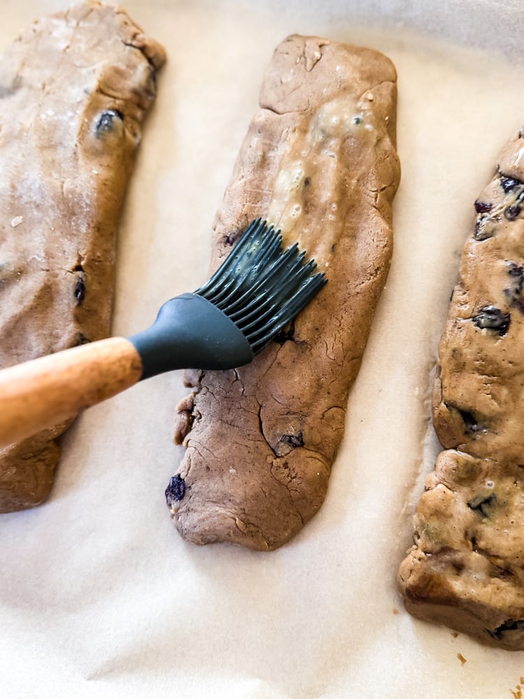 egg wash being brushed on hermit bars on baking pan