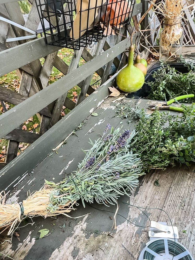 a fresh herb swag on an outdoor potting bench being made