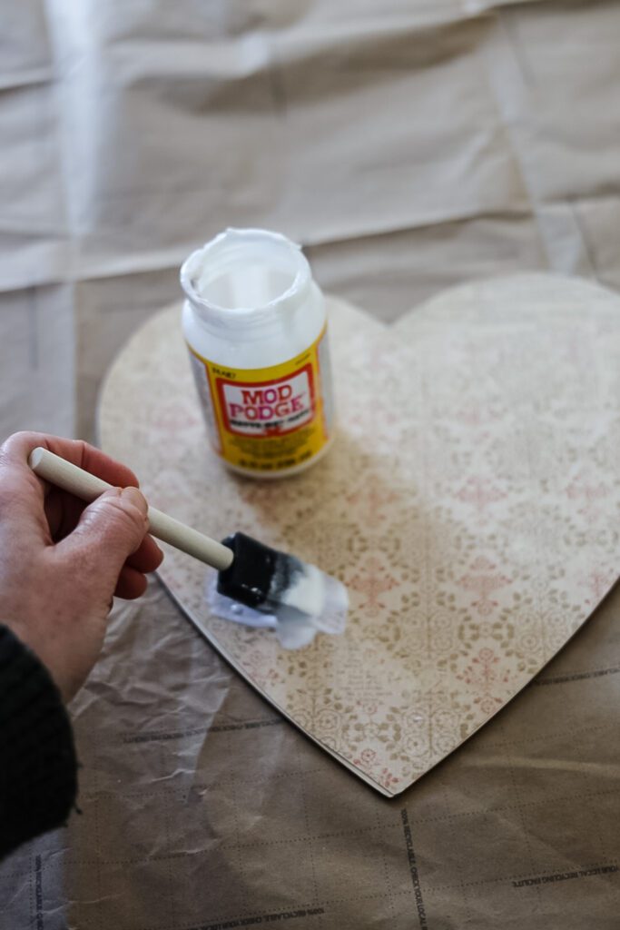 brushing mod podge on a heart diy project