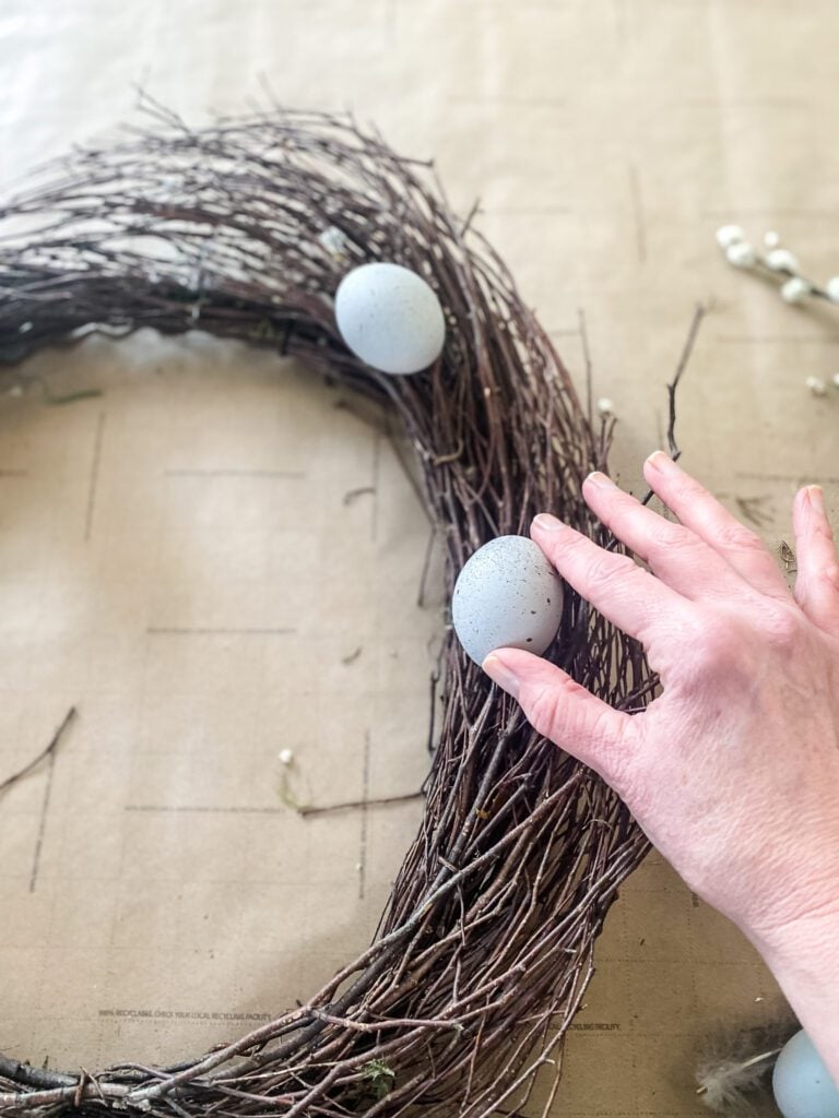 hand adding egg to a wreath