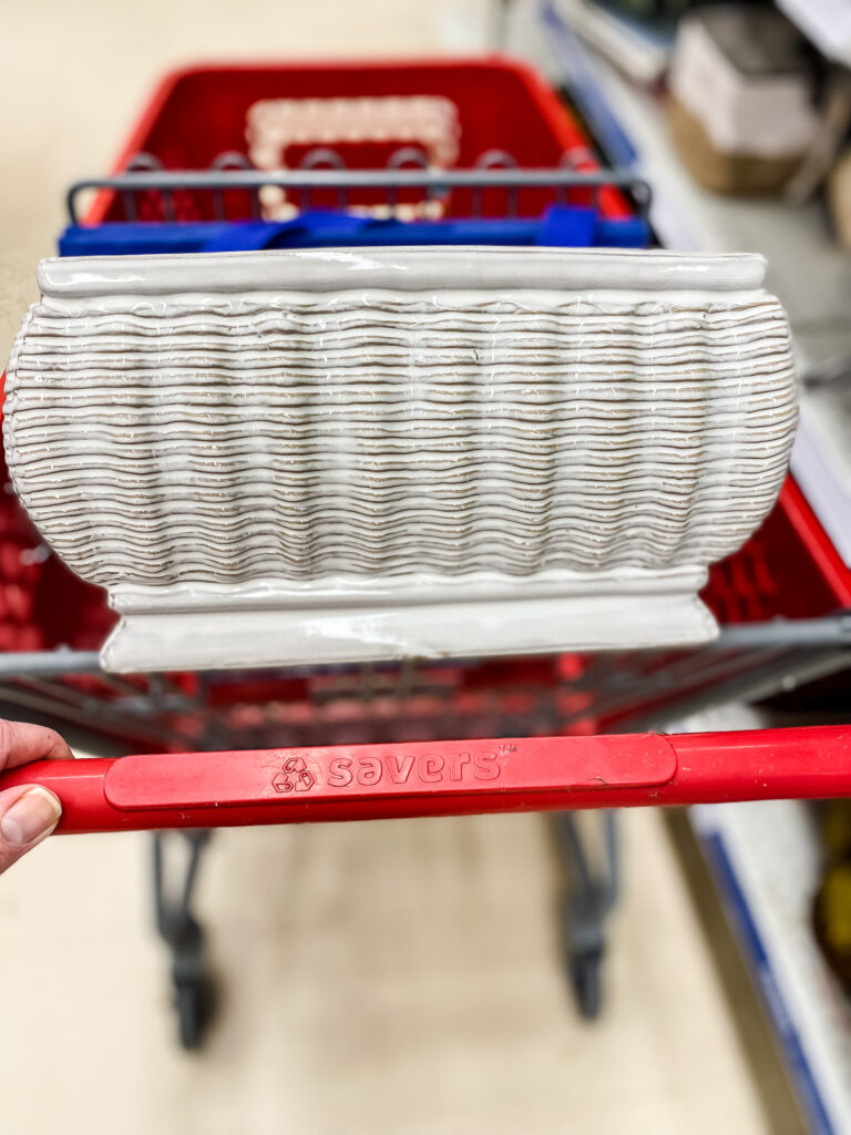 a shopping cart with a white ceramic vase in it