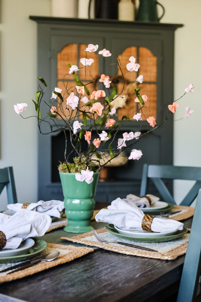 dining table with paper flowers in a green vase