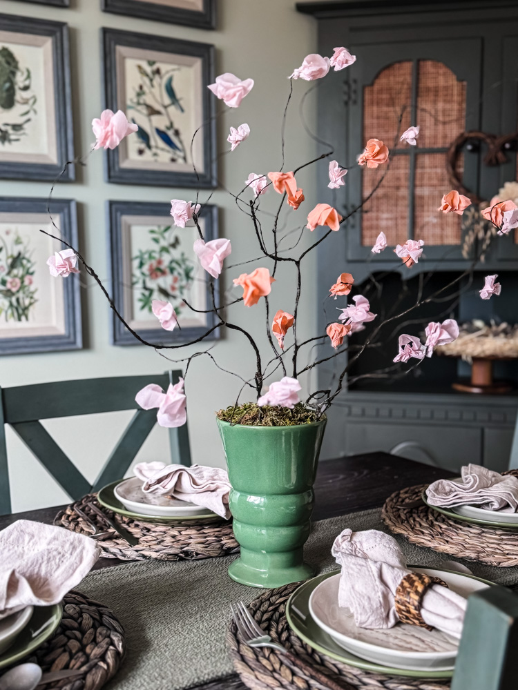 paper cherry blossom stems in green vase on dining table