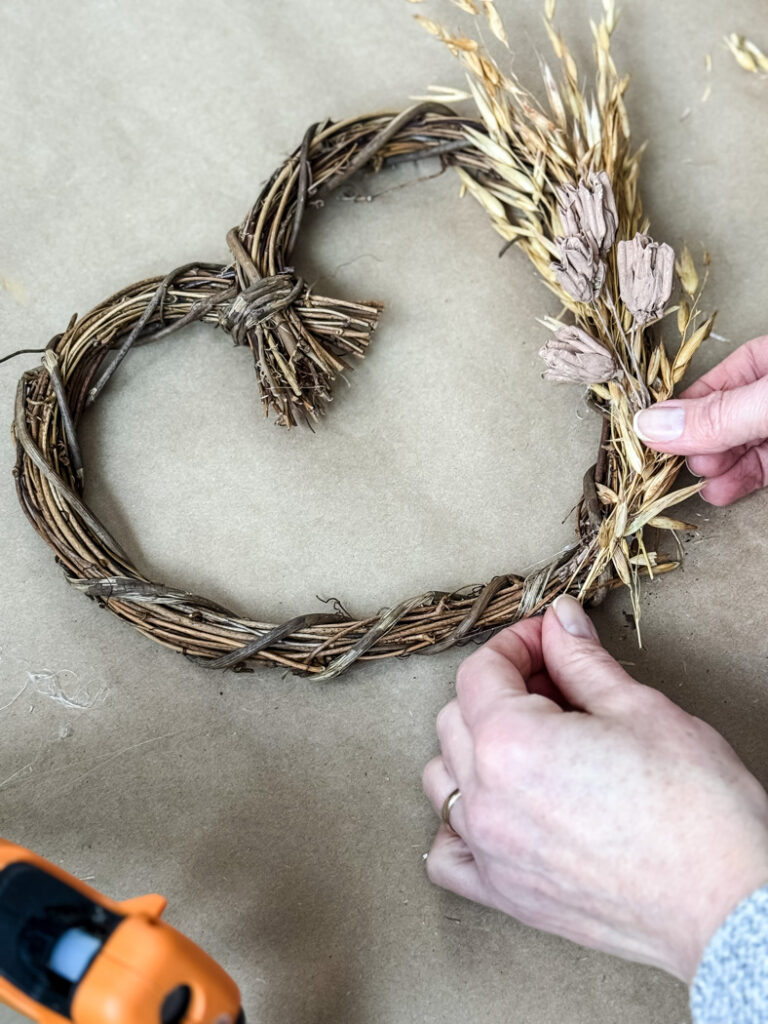 hot gluing flowers to a wreath