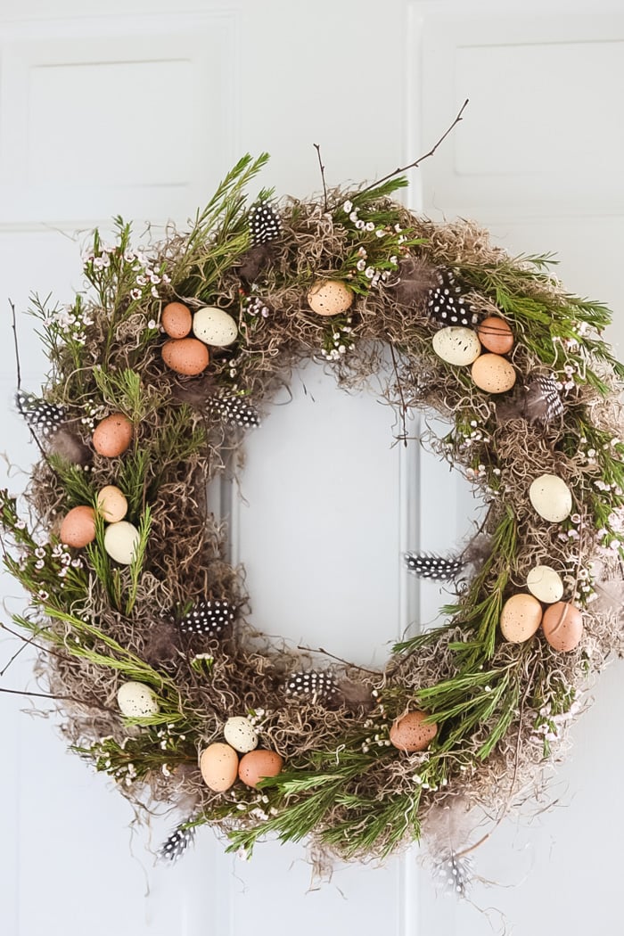 spring wreath hanging on a door that is paintged light blue
