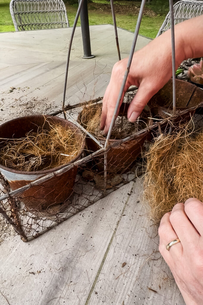 filling a rusty planter with coco liner to house succulents