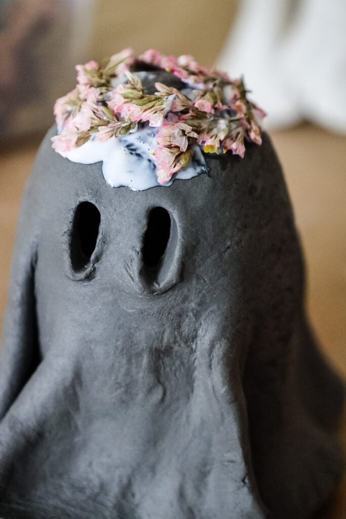 black clay ghost with a flower crown