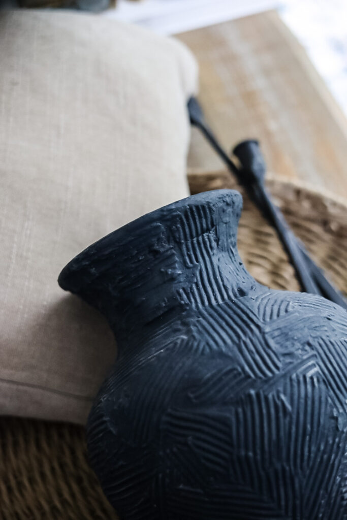 blue vase,beige pillow, black candlesticks, rattan tray