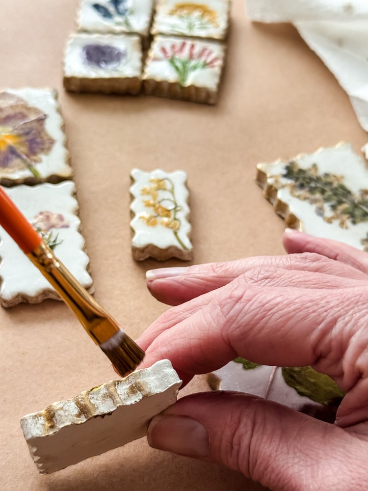 brushing gold rub n buff on the side of a clay magnet project being made