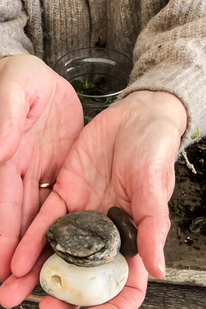 a woman's hand holding 3 beach stones