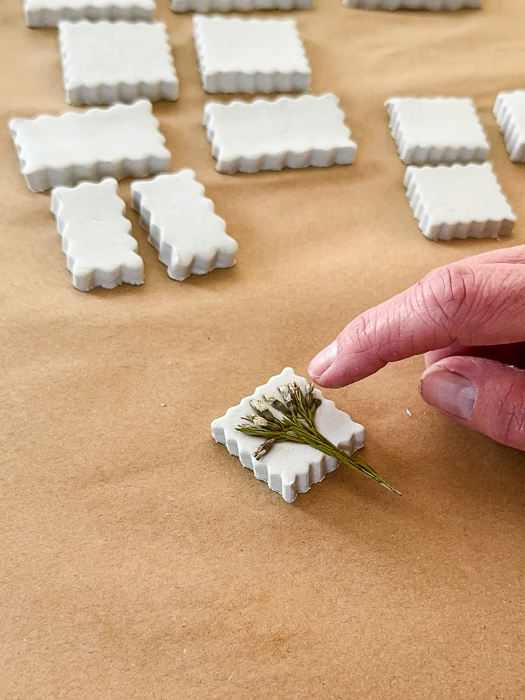 finger pressing flower into clay