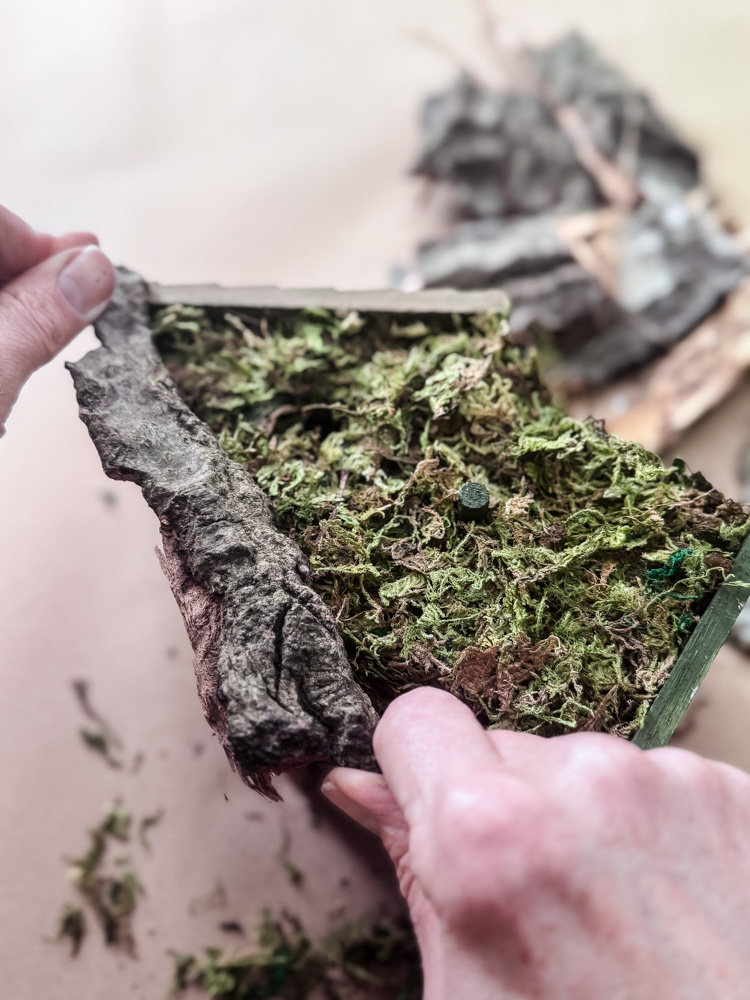 gluing bark onto a birdhouse craft project