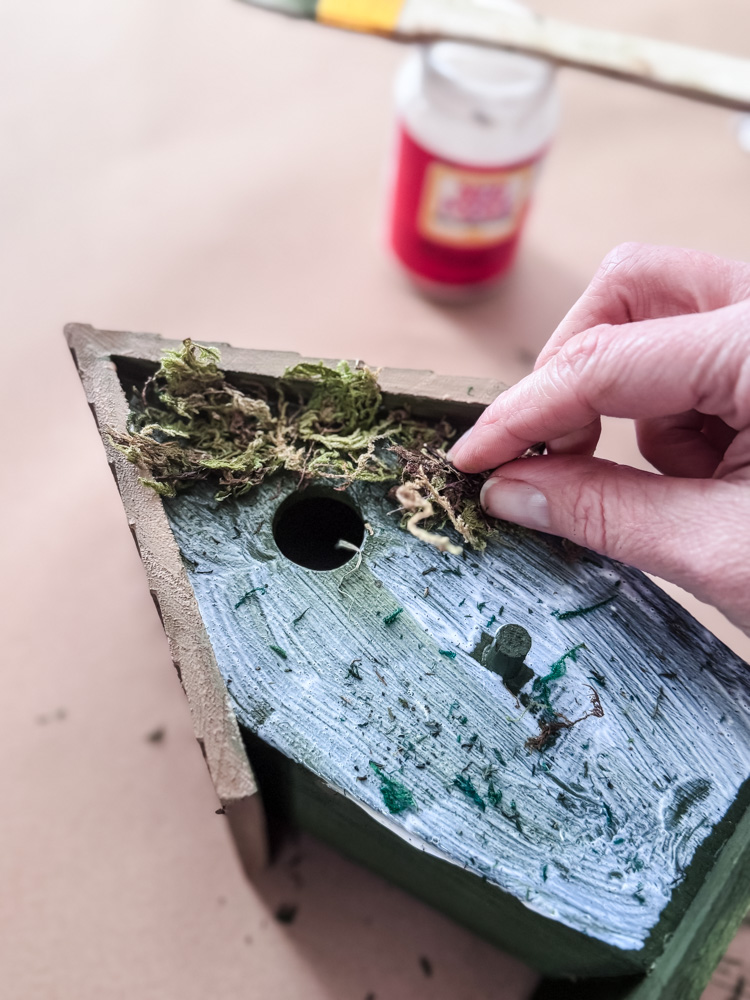 adding moss to a wood birdhouse