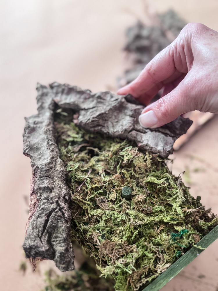 gluing bark onto a craft birdhouse project
