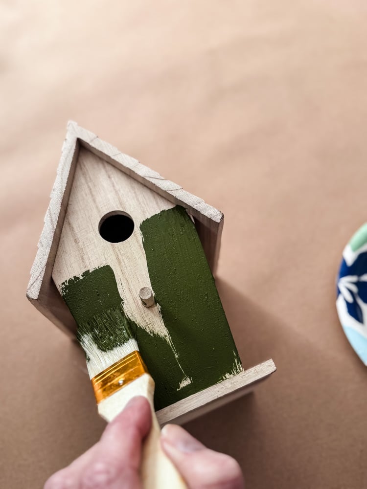 painting a wood birdhouse with green paint