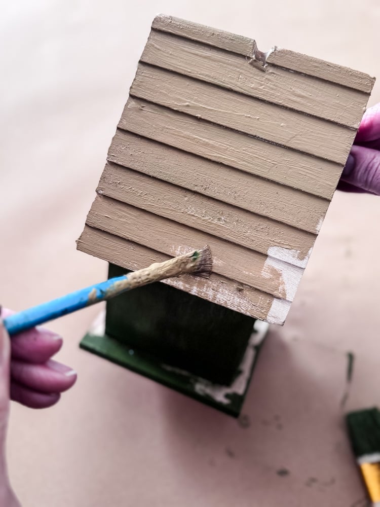 painting the roof of a wood craft birdhouse brown