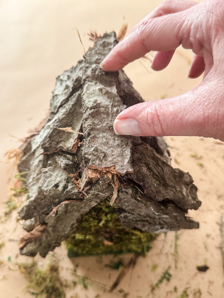 gluing tree bark onto a crafting project of a birdhouse