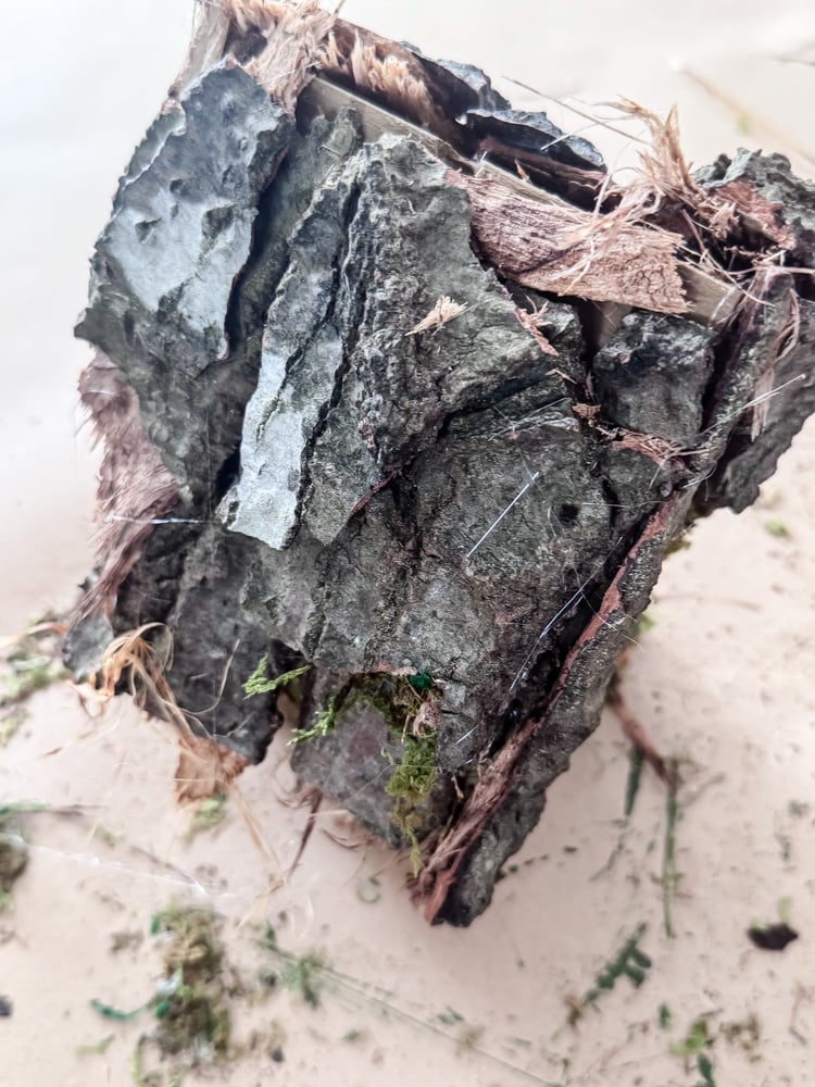 view of a tree bark roof on a craft birdhouse