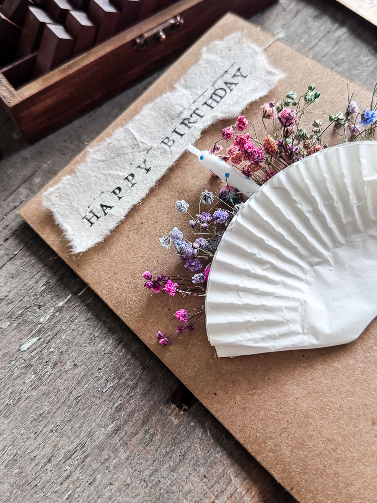 a handmade card that looks like a cupcake but uses colorful flowers for the frosting
