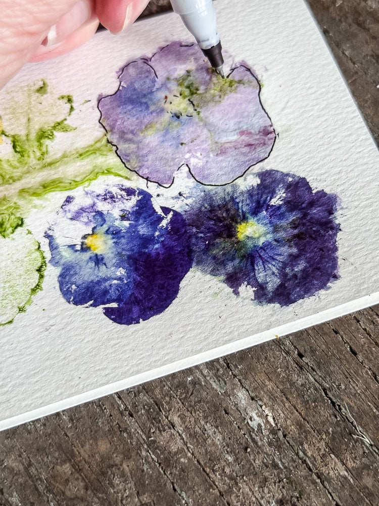 drawing a black marker outline around a pansy print