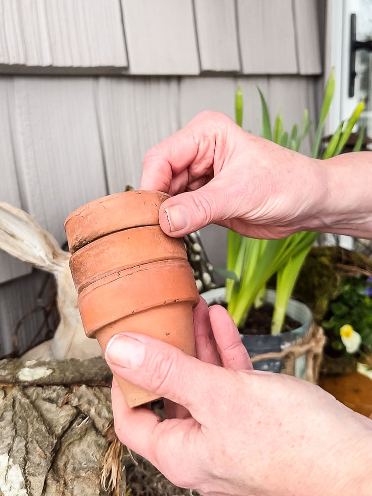 holding a stack of small terracotta pots