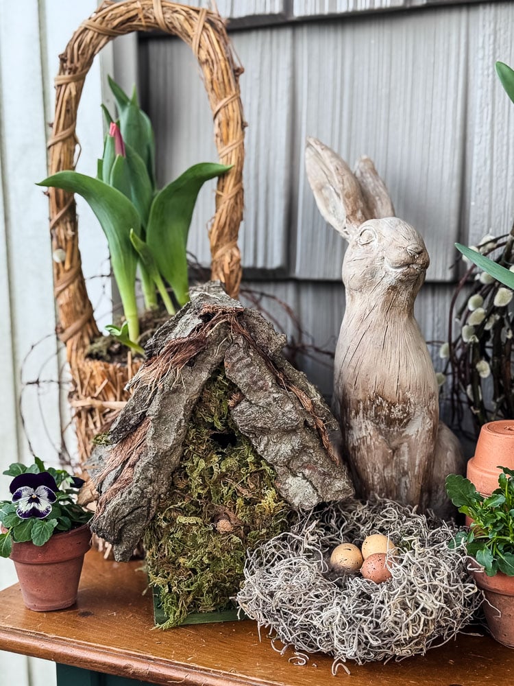 spring table with tulips, nest, birdhouse, and bunny statue