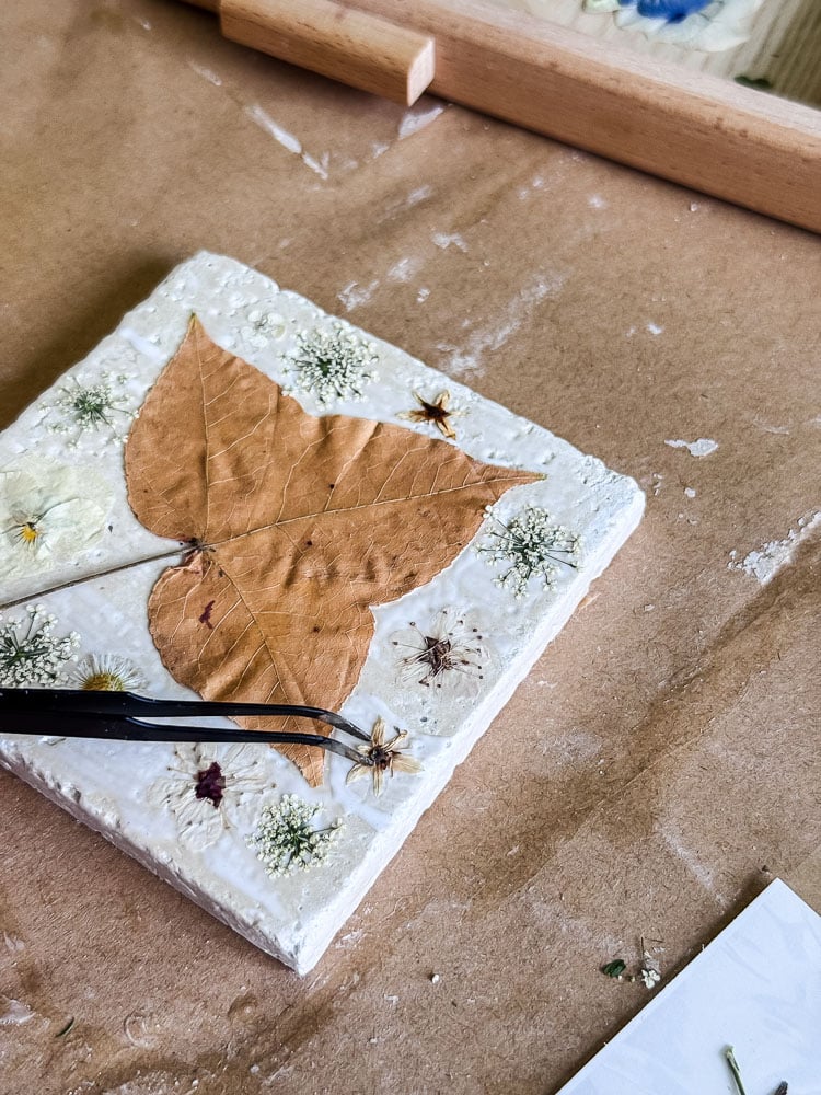 making a tile coaster with a leaf and flowers mod podged to the surface