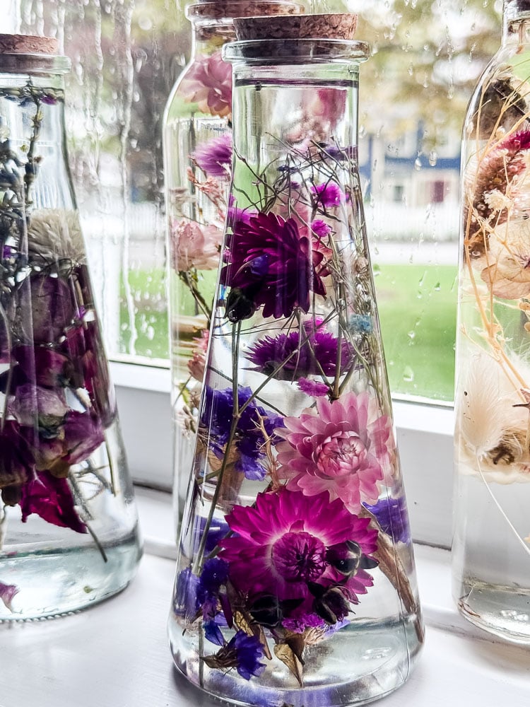 a glass bottle filled with flowers suspended in oil