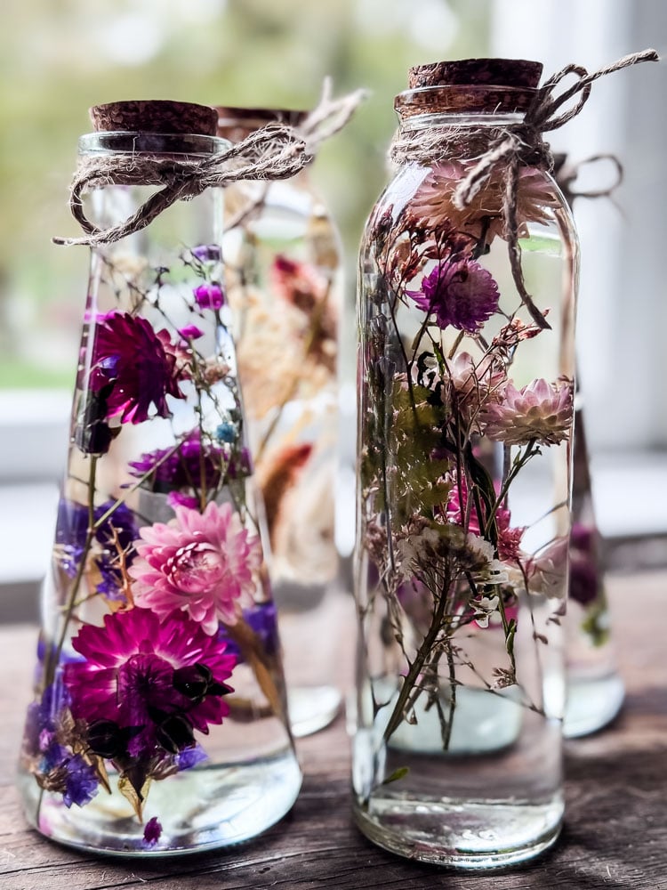 glass bottles with flowers suspended in oil in bright colors