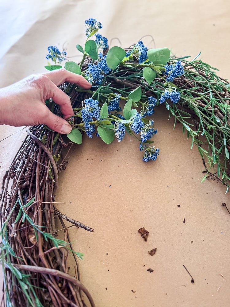 blue floral stem being added to a wreath