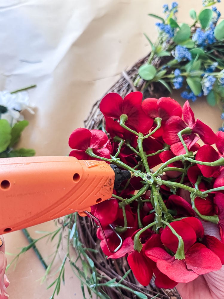 hot glue going on back of red hydrangea faux flower