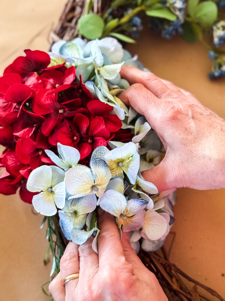 gluing blue hydrangeas to a wreath