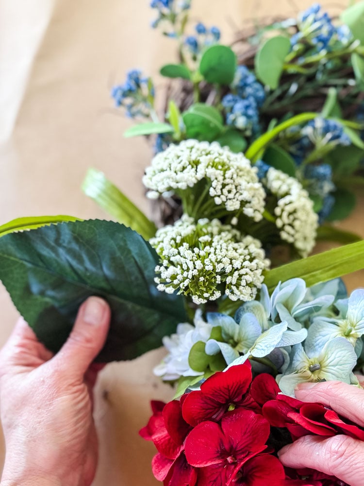 tucking a hydrangea faux leaf into a wreath