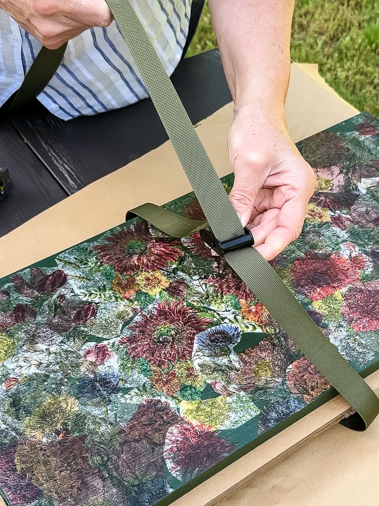 a woman's hand holding a green nylon strap on a flower press
