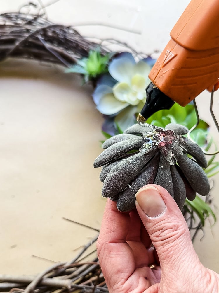 hot gluing a fake succulent to a wreath