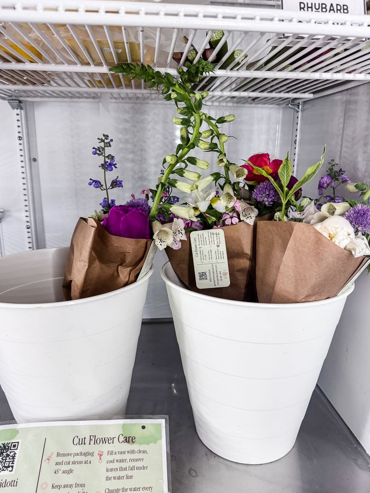 fresh flower bouqets in metal buckets in a cooler