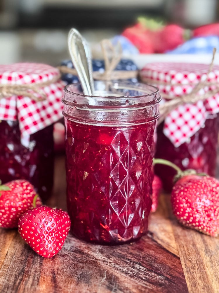 jar of homemade strawberry jam with a spoon in jar