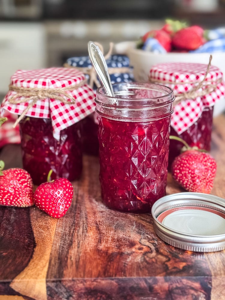 jars of homemade strawberry jam styled with fresh berries