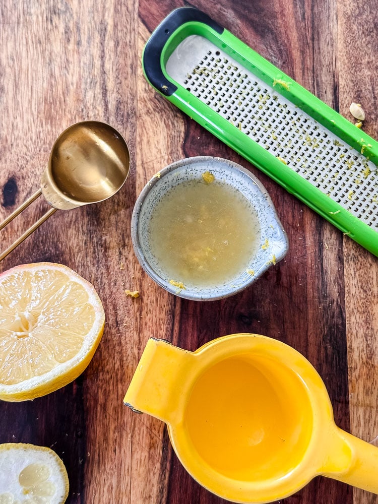 an overview photo of a lemon juicer, lemon juice in a bowl, lemon, and grater