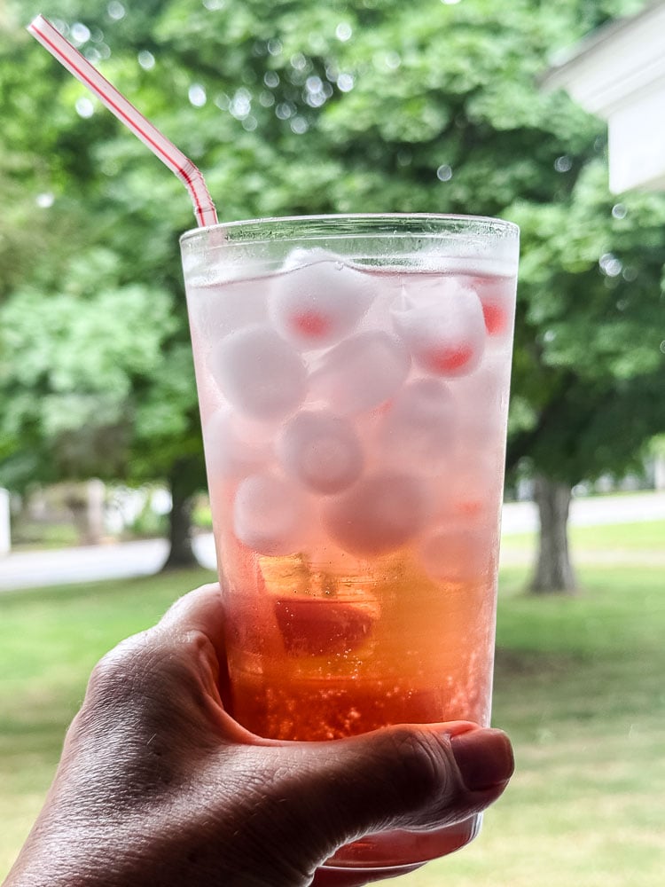a hand holding a glass of strawberry sparkling water