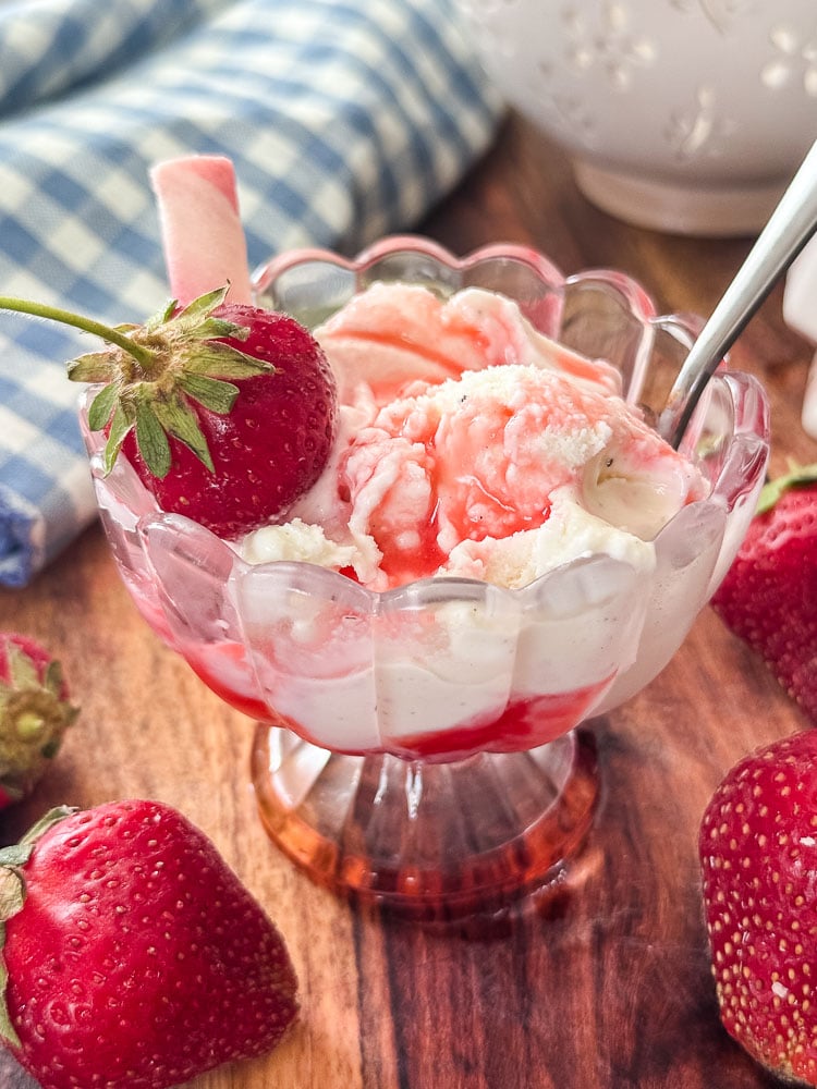 a bowl of vanilla ice cream with strawberrys syrup