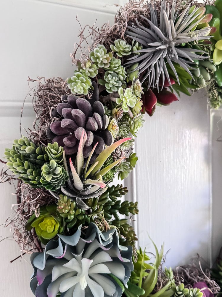 an artificial succulent wreath on a light blue door