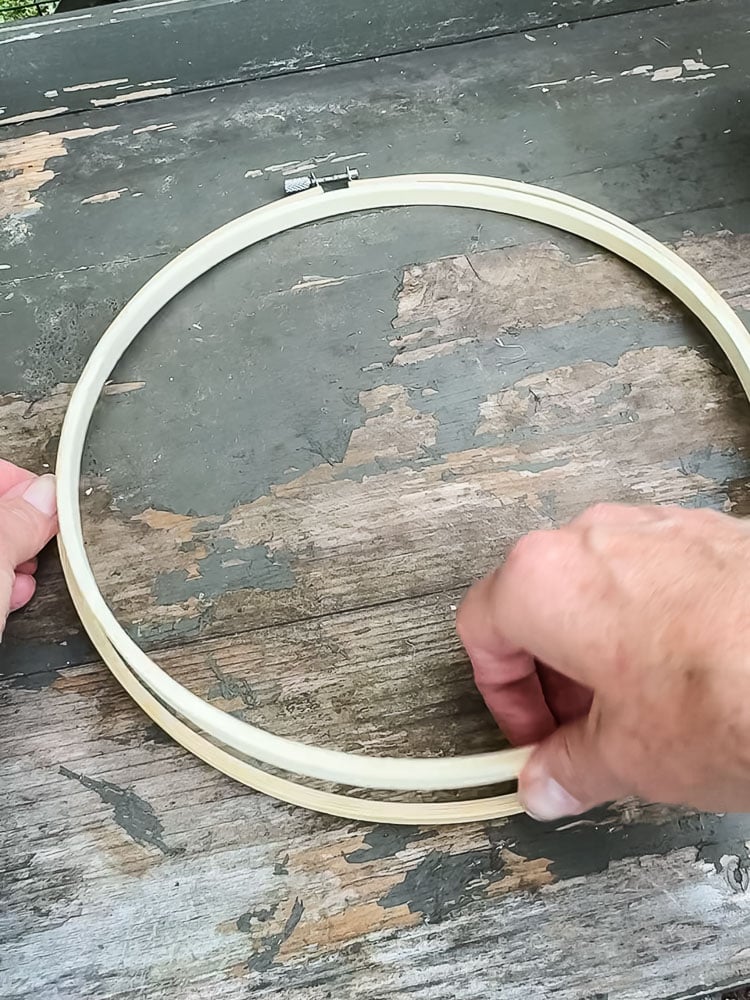 opening up an embroidery hoop on top of a chipped green table