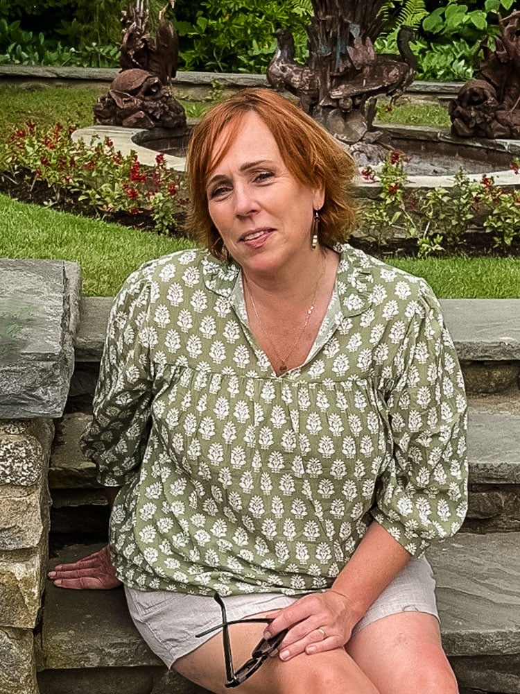 woman in green blouse sitting on bench in a garden