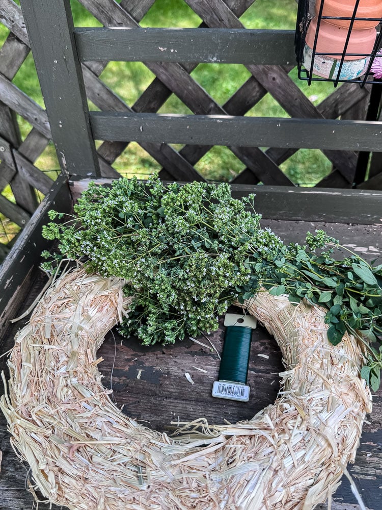 making an herb wreath on a straw wreath form
