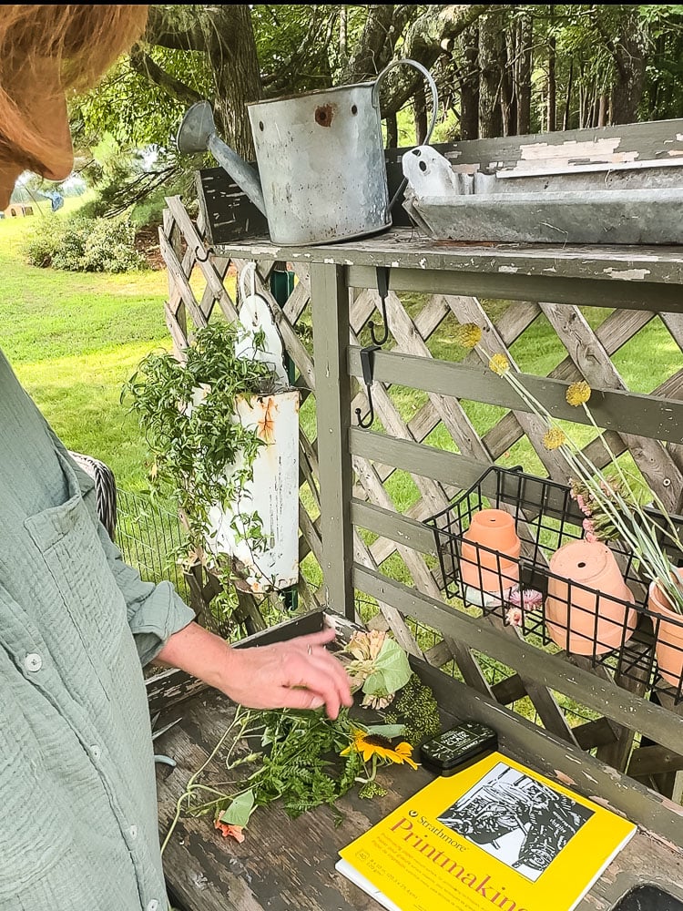 setting up a workpace outdoors to make nature prints with paper, ink pad, and flowers