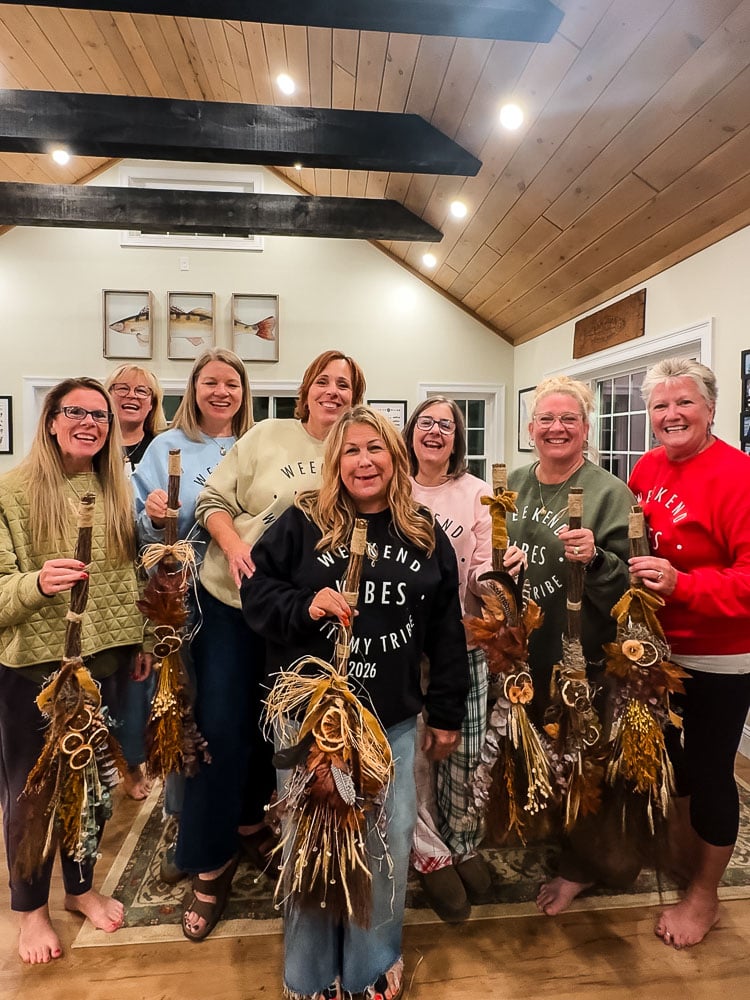 a group of women holding up decorated cinnamon brooms