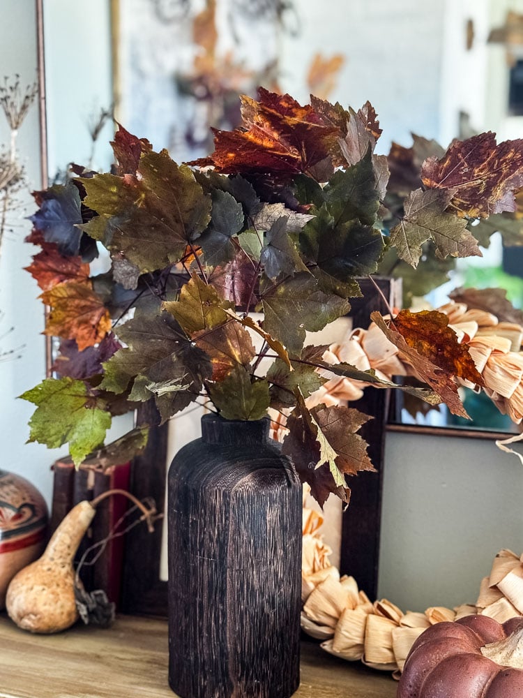 entry table with wood vase of fall leaves
